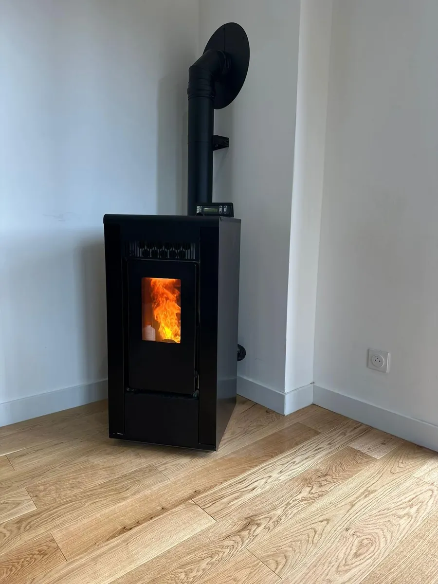Poêle à granulés noir en fonctionnement, flamme visible, installé dans une pièce de vie sur parquet clair