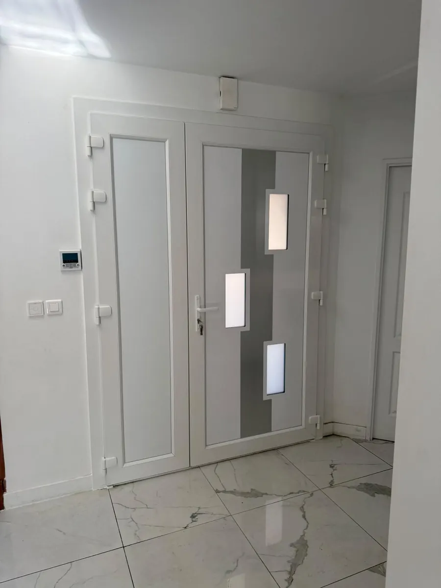 Porte d'entrée PVC blanche à vitrages décoratifs vue depuis l'intérieur, sol carrelé